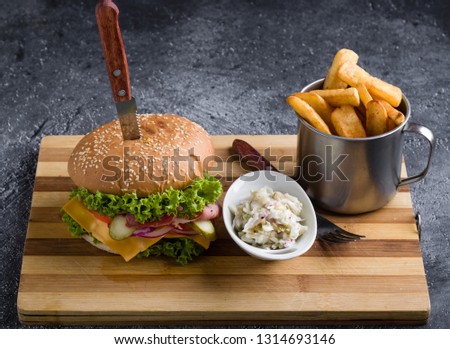 tasty rustic hamburger with fries on wooden table