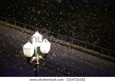 A street light post lamp on a snowy dark winter night