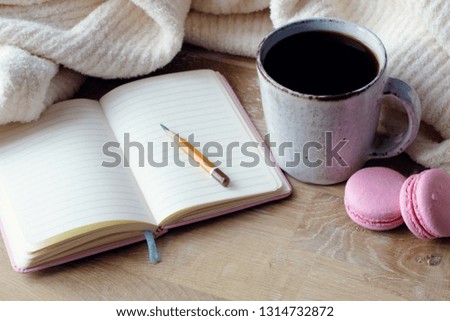 Empty notepad, coffee and macaron on wood desk perspective view. Vintage photo, toning. Fashion flat lay.