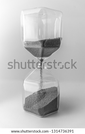 Hourglass with sand falling on white background. Sand running through the bulbs of an hourglass measuring the passing time in a countdown to a deadline
