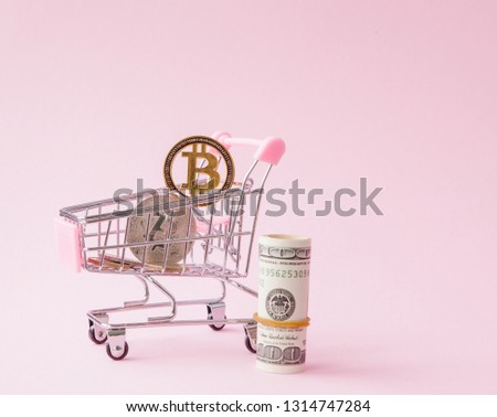 Shopping cart with bitcoin coin and dollars on pink background with Copy Space.