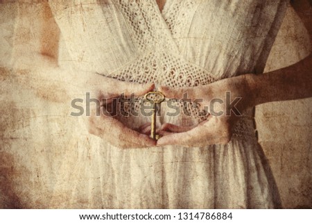 Woman holding old key in a hands and stay near window with natural light