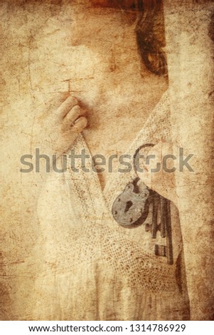 Woman holding old key and lock in a hands and stay near window with natural light