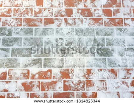 Sidewalk colored tiles with snow and traces of shoes in the winter on the streets 
