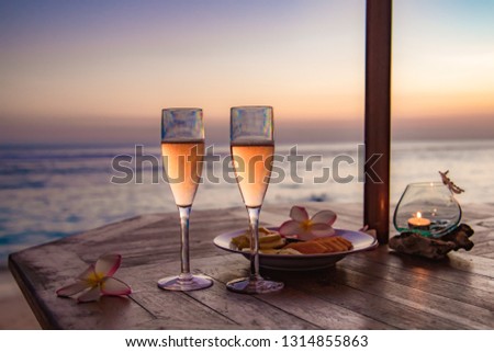 Glasses of champagne on the beach with a red sunset Royalty-Free Stock Photo #1314855863