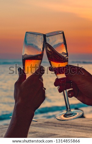 Glasses of champagne on the beach with a red sunset Royalty-Free Stock Photo #1314855866