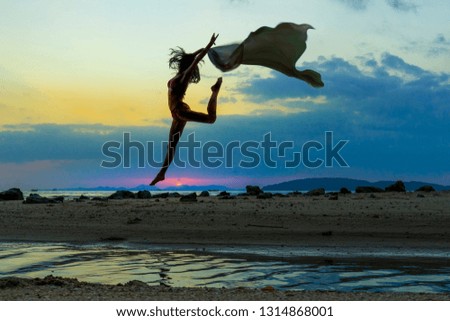 Silhouette young bikini woman jumping over the sunset at Ao Nang, Krabi Province, Thailand. Successful concept image.