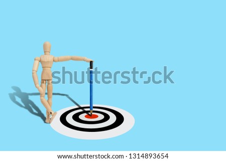 Business Planning Concept : Wooden figure mannequin holding pencil hit target on dart board.