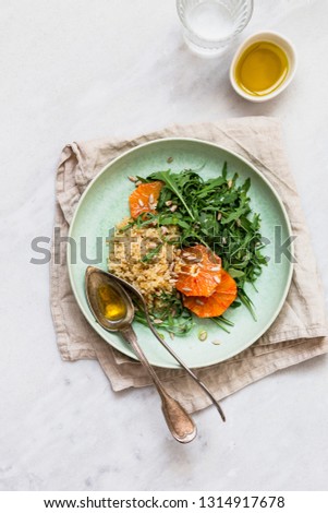 Vegan salad with quinoa, rucola, seeds, orange seasoned with olive oil. Healthy eating concept