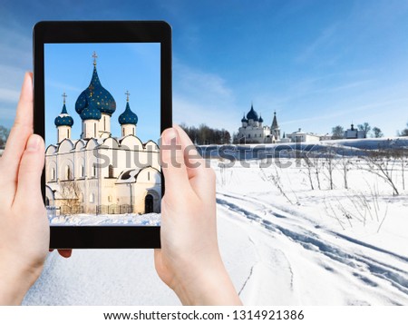 travel concept - tourist photographs of Kremlin with Nativity of the Virgin (Nativity of the Theotokos) Chathedral and Palace in Suzdal town in Russia on smartphone in winter