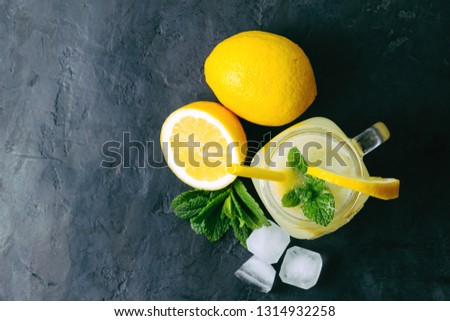Refreshing lemonade drink with lemon slice and mint in the jar on dark background, top view.