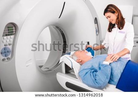 Radiographer reassuring senior man going into CT scanner in hospital Royalty-Free Stock Photo #1314962018