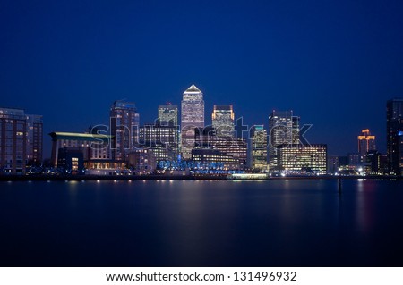 Canary Wharf at night. Illuminated financial district skyline in London, UK. Office windows lights on the skyscrapers of the business district at dusk. Reflection on River Thames. Royalty-Free Stock Photo #131496932