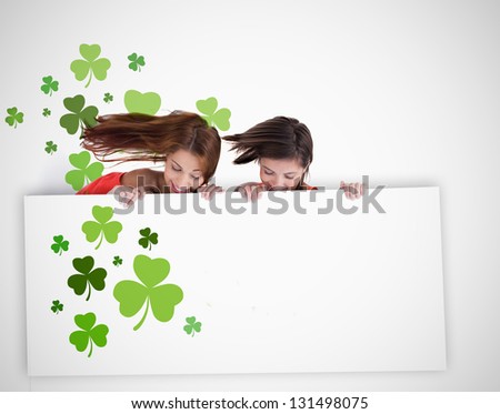 Girls looking down at blank placard with shamrocks on white background for st patricks day advertisment
