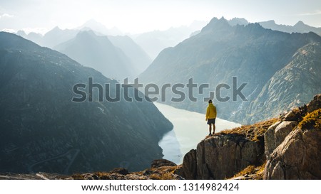 
Man on top of mountain. Epic shot of adventure hiking in mountains alone outdoor active lifestyle travel vacations. Conceptual scene.  Royalty-Free Stock Photo #1314982424