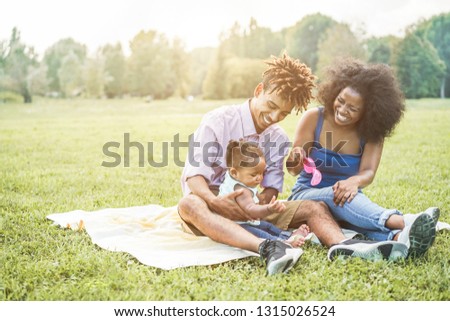 Happy black family having fun doing picnic outdoor - Parents and their daughter enjoying time together in a weekend day - Love tender moment and happiness concept - Focus on father and mother on faces