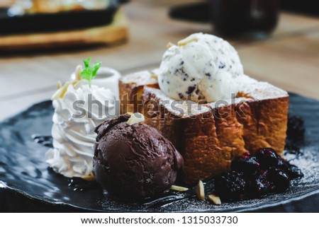 Chocolate ice cream with blueberries in a black plate, chocolate chips and ice cream are blurred picture in the dish.