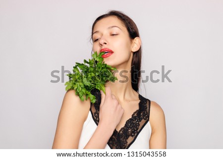Beautiful smiling girl with parsley. Photo of fashion female on gray background. Close up. Healthy lifestyle concept. Parsley contains many vitamins.