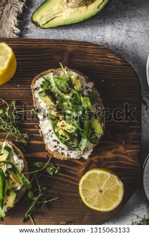 Delish fresh cheese on crisp bread, fresh cheese with avocado and cucumber and healthy seeds on top