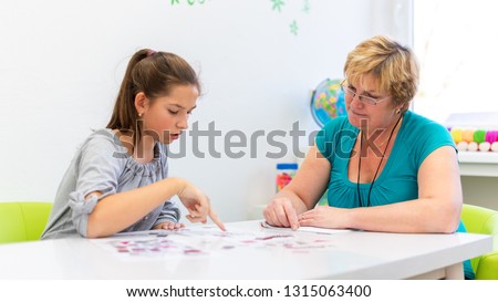 Mature female therapist working with a teenage girl with learning difficulties to master logical tests. Royalty-Free Stock Photo #1315063400