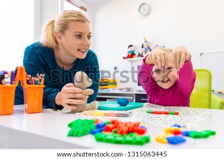 Toddler girl in child occupational therapy session doing sensory playful exercises with her therapist.  Royalty-Free Stock Photo #1315063445