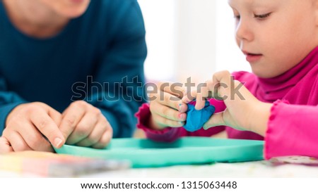 Toddler girl in child occupational therapy session doing sensory playful exercises with her therapist.  Royalty-Free Stock Photo #1315063448