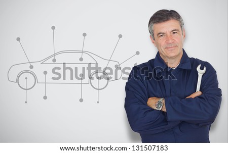 Mature mechanic standing next to car diagram while looking at camera