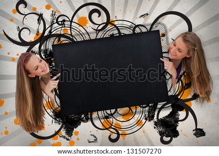 Girls pointing to black copy space on artistic swirl design background