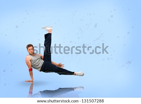 Break dancer balancing on one hand on blue background
