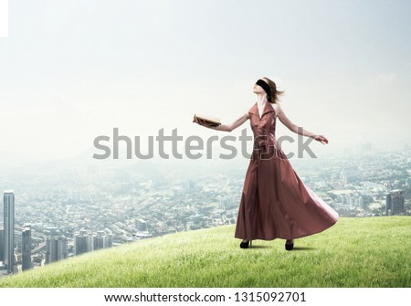 Young woman in red long dress and blindfold with book in hand