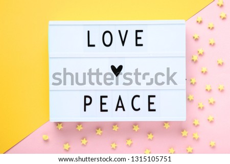 Lightbox with words Love Peace with paper stars on colorful background