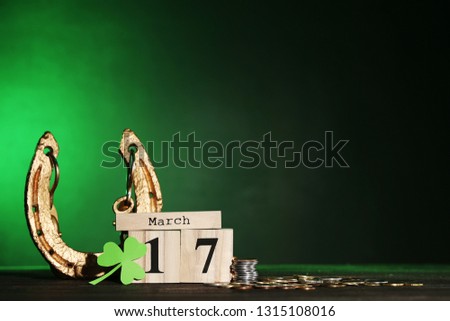 St.Patrick's Day. Golden horseshoe with clover leaf, coins and wooden calendar