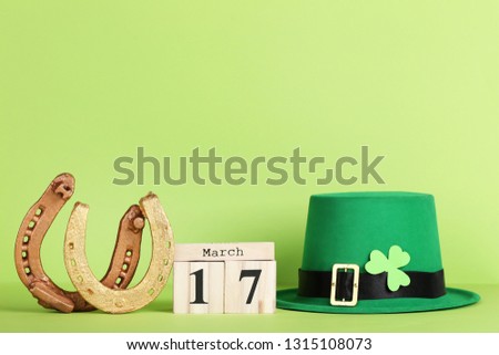 St.Patrick's Day. Golden horseshoes with green hat, wooden calendar and clover leaf