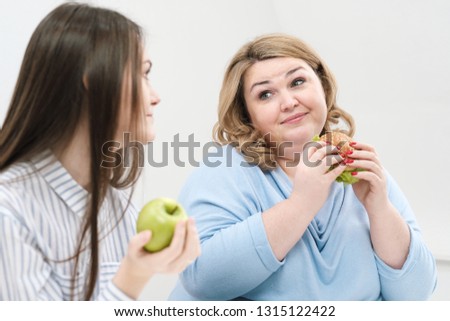 Slender girl eats healthy food, Fat woman eats harmful fast food. On a white background, the theme of diet and proper nutrition, choice and opposition.