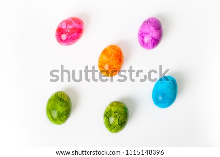Flat lay of colorful painted easter eggs laying on white background
