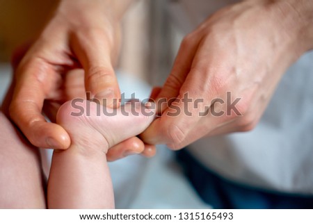 Picture of hands of massage therapist making foot massage to small child.
