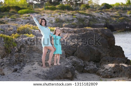 Happy loving family mother and daughter having fun on the beach at sunset - Mum playing with her kid next see in holidays - Parent, vacation, family lifestyle concept