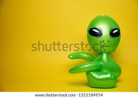 green alien looks,yellow background