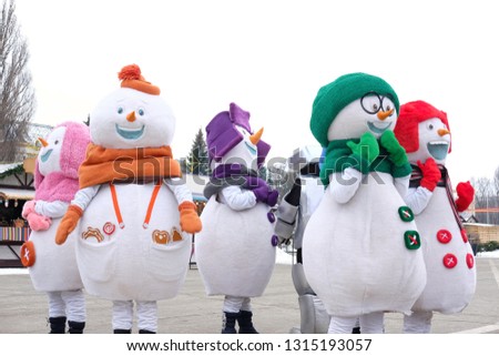 snowmen dance on a festive area near the carousel where they spend the winter holidays, the theme of holidays and entertainment
