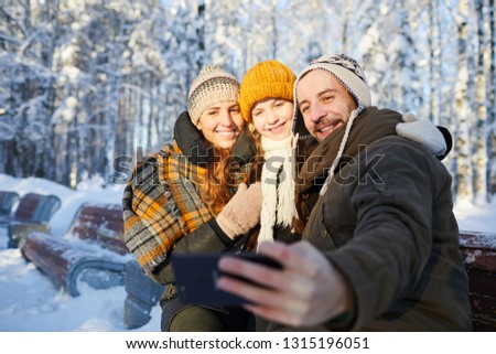 Portrait of happy family taking selfie photo in beautiful winter forest, copy space