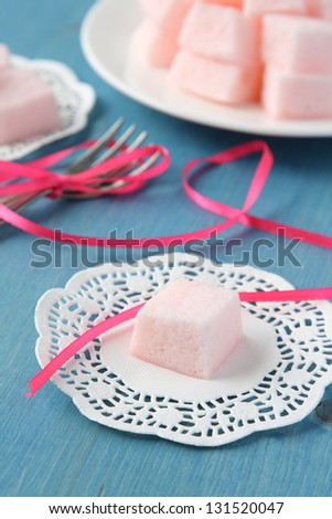Homemade pink marshmallows on blue wooden background, selective focus