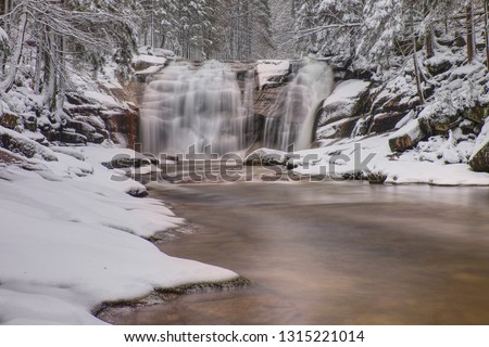 Frozen waterfall in the forest. Winter view into valley of Mumlava river, Czech republic. Winter and winter landscapes.
