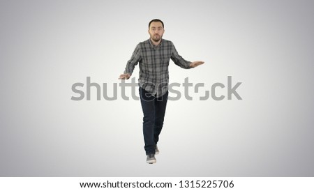 Young man in a casual outfit walking and dancing on gradient background.