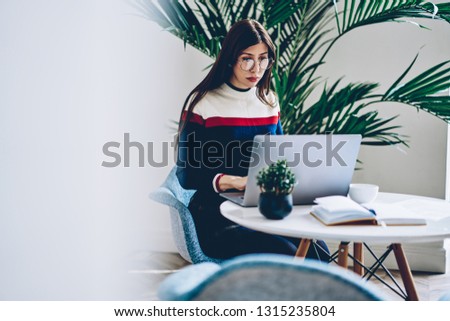 Woman in optical eyewear for provide eyes protection reading received email from colleague with information for office schedule connected to home wireless internet on computer during distance job