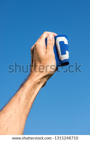Man's hand holding the soccer captain armband