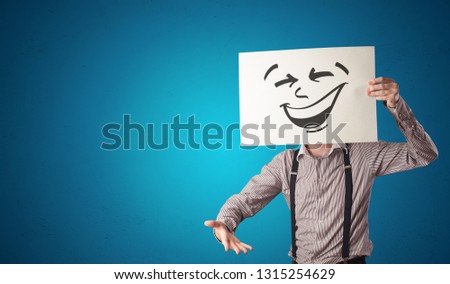 Casual person holding a paper with cool emoticon in front of his face