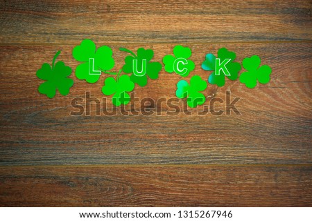 Green paper LUCK LUCKY lettering on dark barn wood rustic background. Green clover shamrock leaves. St. Patrick's Day 
