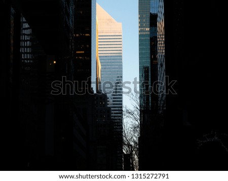 Business buildings in downtown New York, USA. Midtown Manhattan silhouette buildings. Blue sky, dramatic lighting. 
