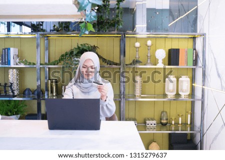 happiness young asian muslim woman holding credit card and using laptop computer. Online shopping concept 