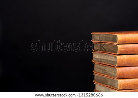 Pile of brown books on black background. Copy space.